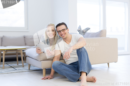 Image of couple relaxing at  home with tablet computers