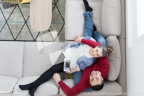 Image of couple relaxing at  home with tablet computers