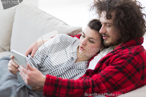 Image of couple relaxing at  home with tablet computers