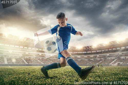 Image of Young boy with soccer ball doing flying kick at stadium