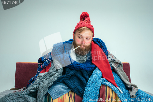 Image of Bearded Man with Flue Sitting on Sofa at Home. Healthcare Concepts.