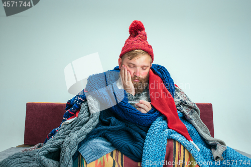 Image of Bearded Man with Flue Sitting on Sofa at Home. Healthcare Concepts.