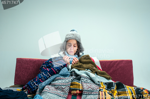 Image of The young woman with Flue Sitting on Sofa at Home. Healthcare Concepts.