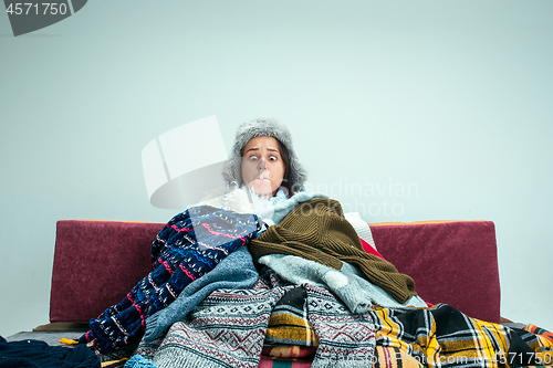 Image of The young woman with Flue Sitting on Sofa at Home. Healthcare Concepts.