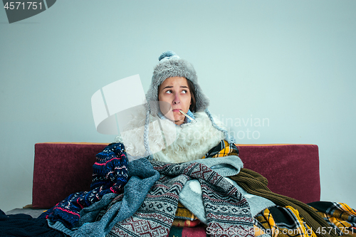 Image of The young woman with Flue Sitting on Sofa at Home. Healthcare Concepts.