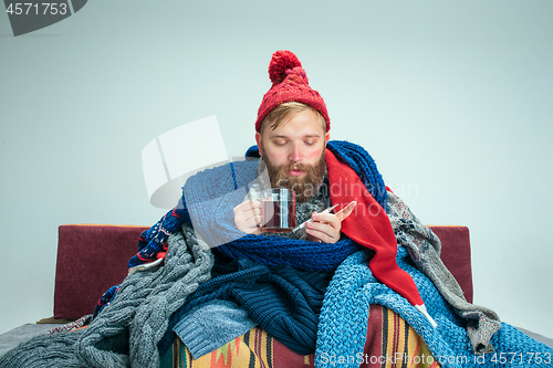 Image of Bearded Man with Flue Sitting on Sofa at Home. Healthcare Concepts.