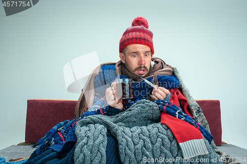 Image of Bearded Man with Flue Sitting on Sofa at Home. Healthcare Concepts.
