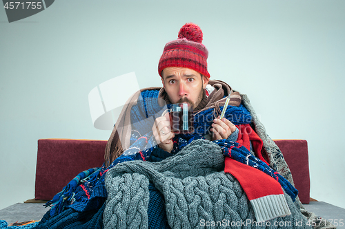 Image of Bearded Man with Flue Sitting on Sofa at Home. Healthcare Concepts.