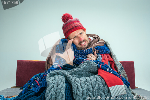 Image of Bearded Man with Flue Sitting on Sofa at Home. Healthcare Concepts.