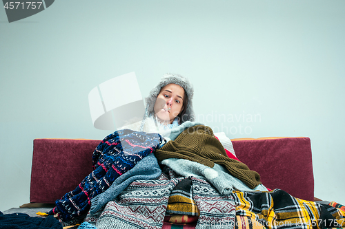 Image of The young woman with Flue Sitting on Sofa at Home. Healthcare Concepts.