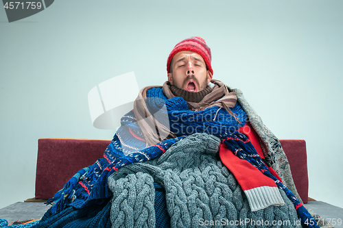 Image of Bearded Man with Flue Sitting on Sofa at Home. Healthcare Concepts.