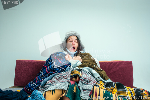 Image of The young woman with Flue Sitting on Sofa at Home. Healthcare Concepts.