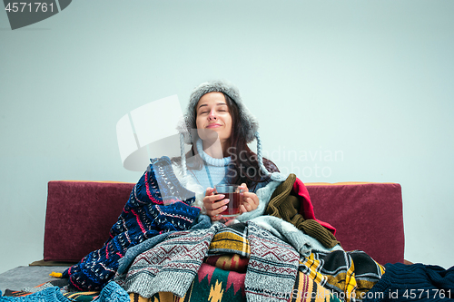 Image of The young woman with Flue Sitting on Sofa at Home. Healthcare Concepts.