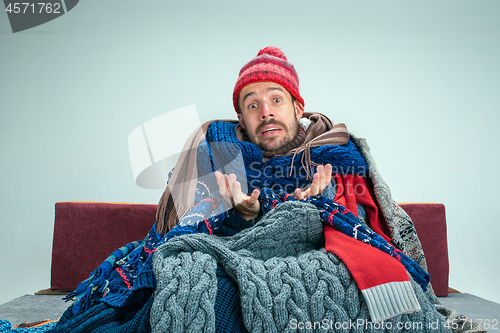 Image of Bearded Man with Flue Sitting on Sofa at Home. Healthcare Concepts.