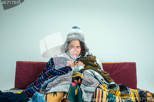 Image of The young woman with Flue Sitting on Sofa at Home. Healthcare Concepts.