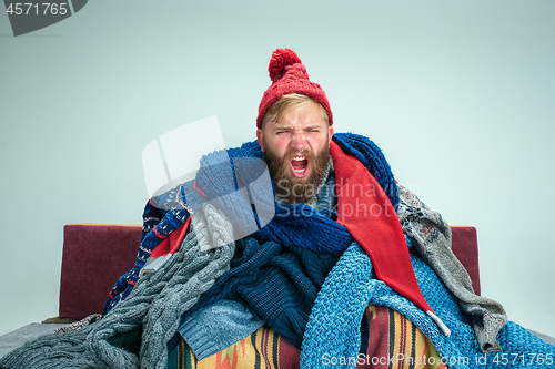 Image of Bearded Man with Flue Sitting on Sofa at Home. Healthcare Concepts.