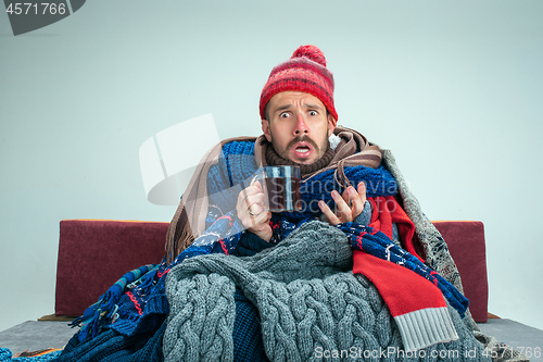 Image of Bearded Man with Flue Sitting on Sofa at Home. Healthcare Concepts.