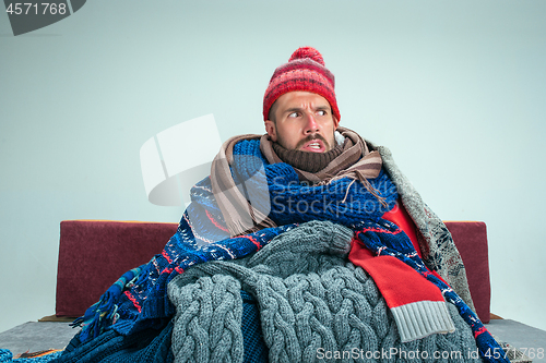 Image of Bearded Man with Flue Sitting on Sofa at Home. Healthcare Concepts.