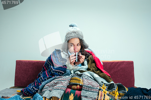 Image of The young woman with Flue Sitting on Sofa at Home. Healthcare Concepts.