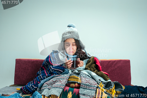 Image of The young woman with Flue Sitting on Sofa at Home. Healthcare Concepts.