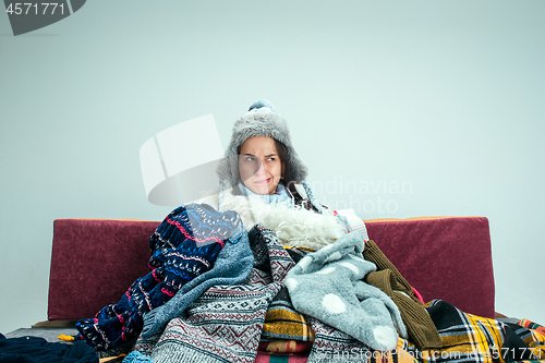 Image of The young woman with Flue Sitting on Sofa at Home. Healthcare Concepts.