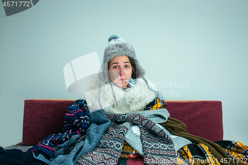 Image of The young woman with Flue Sitting on Sofa at Home. Healthcare Concepts.