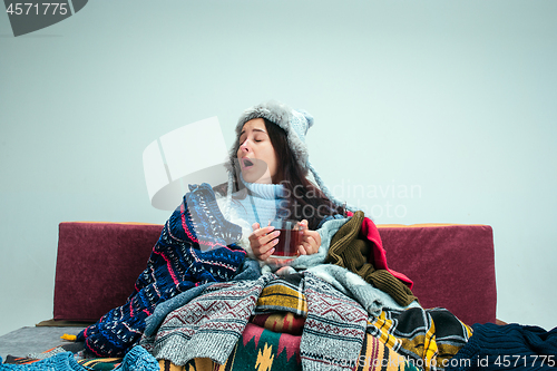 Image of The young woman with Flue Sitting on Sofa at Home. Healthcare Concepts.