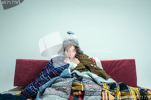 Image of The young woman with Flue Sitting on Sofa at Home. Healthcare Concepts.