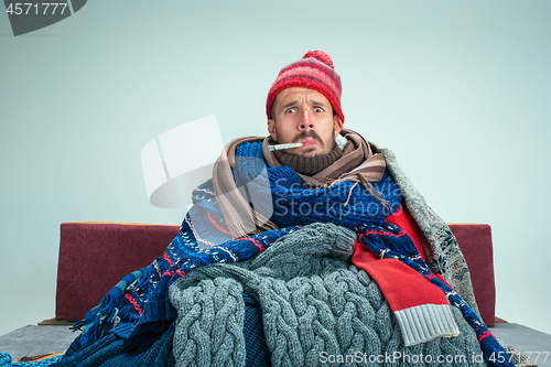 Image of Bearded Man with Flue Sitting on Sofa at Home. Healthcare Concepts.