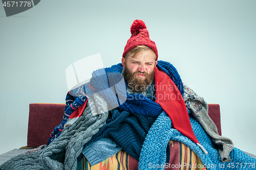 Image of Bearded Man with Flue Sitting on Sofa at Home. Healthcare Concepts.