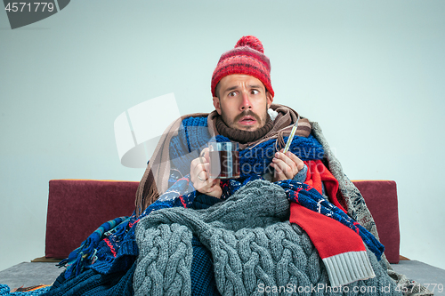 Image of Bearded Man with Flue Sitting on Sofa at Home. Healthcare Concepts.