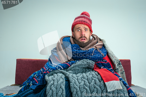 Image of Bearded Man with Flue Sitting on Sofa at Home. Healthcare Concepts.