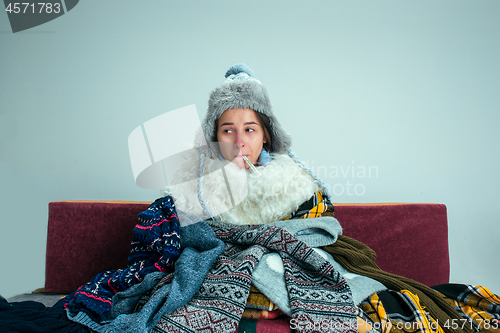 Image of The young woman with Flue Sitting on Sofa at Home. Healthcare Co