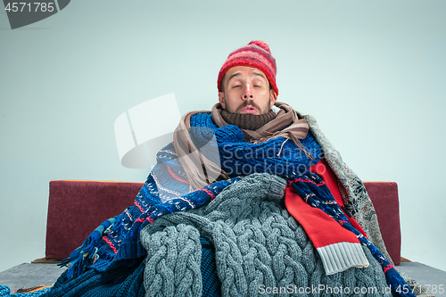 Image of Bearded Man with Flue Sitting on Sofa at Home. Healthcare Concepts.