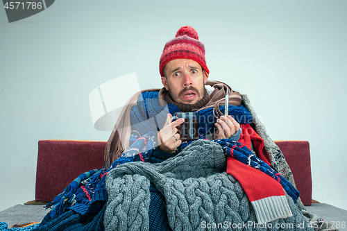 Image of Bearded Man with Flue Sitting on Sofa at Home. Healthcare Concepts.