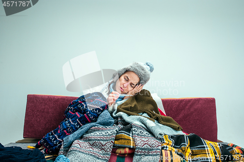 Image of The young woman with Flue Sitting on Sofa at Home. Healthcare Concepts.