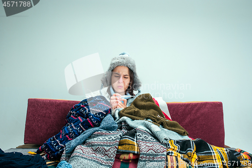 Image of The young woman with Flue Sitting on Sofa at Home. Healthcare Concepts.