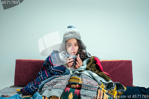 Image of The young woman with Flue Sitting on Sofa at Home. Healthcare Concepts.