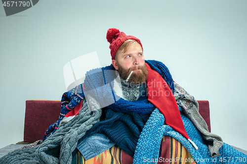 Image of Bearded Man with Flue Sitting on Sofa at Home. Healthcare Concepts.