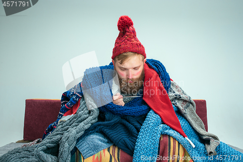 Image of Bearded Man with Flue Sitting on Sofa at Home. Healthcare Concepts.