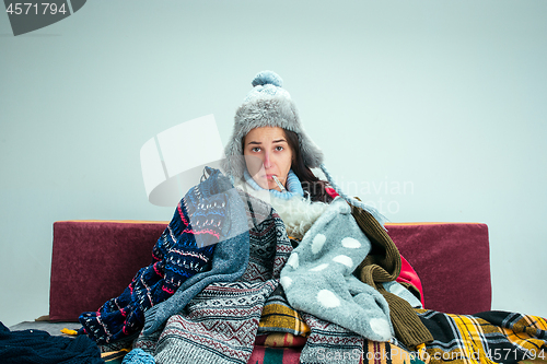 Image of The young woman with Flue Sitting on Sofa at Home. Healthcare Concepts.