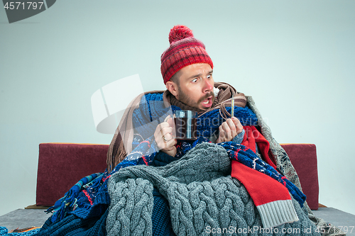 Image of Bearded Man with Flue Sitting on Sofa at Home. Healthcare Concepts.