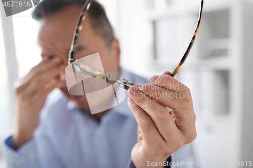 Image of hand of tired businessman with glasses at office