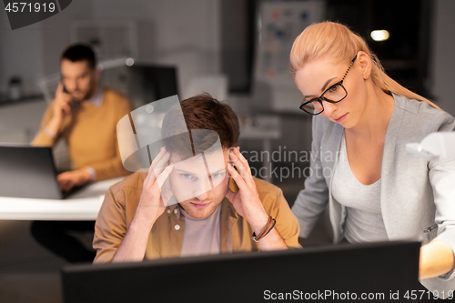 Image of business team with computer working late at office