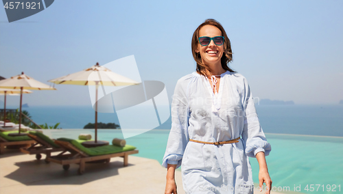 Image of happy woman walking over infinity edge pool