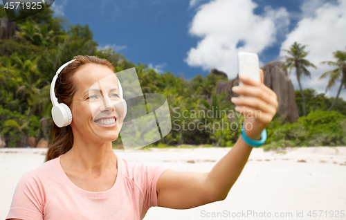 Image of woman in phones takes selfie by cellphone on beach