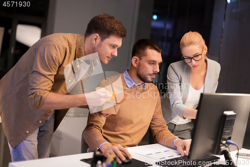 Image of business team with computer working late at office