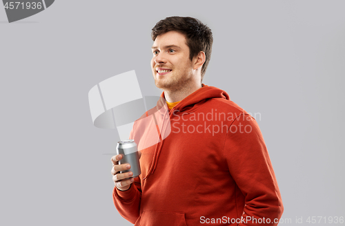 Image of happy young man drinking soda from tin can