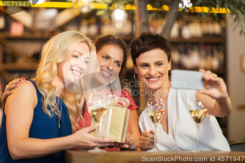 Image of women with gift taking selfie at wine bar