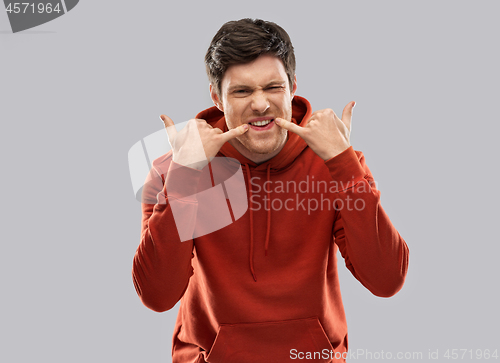 Image of bully young man whistling over grey background